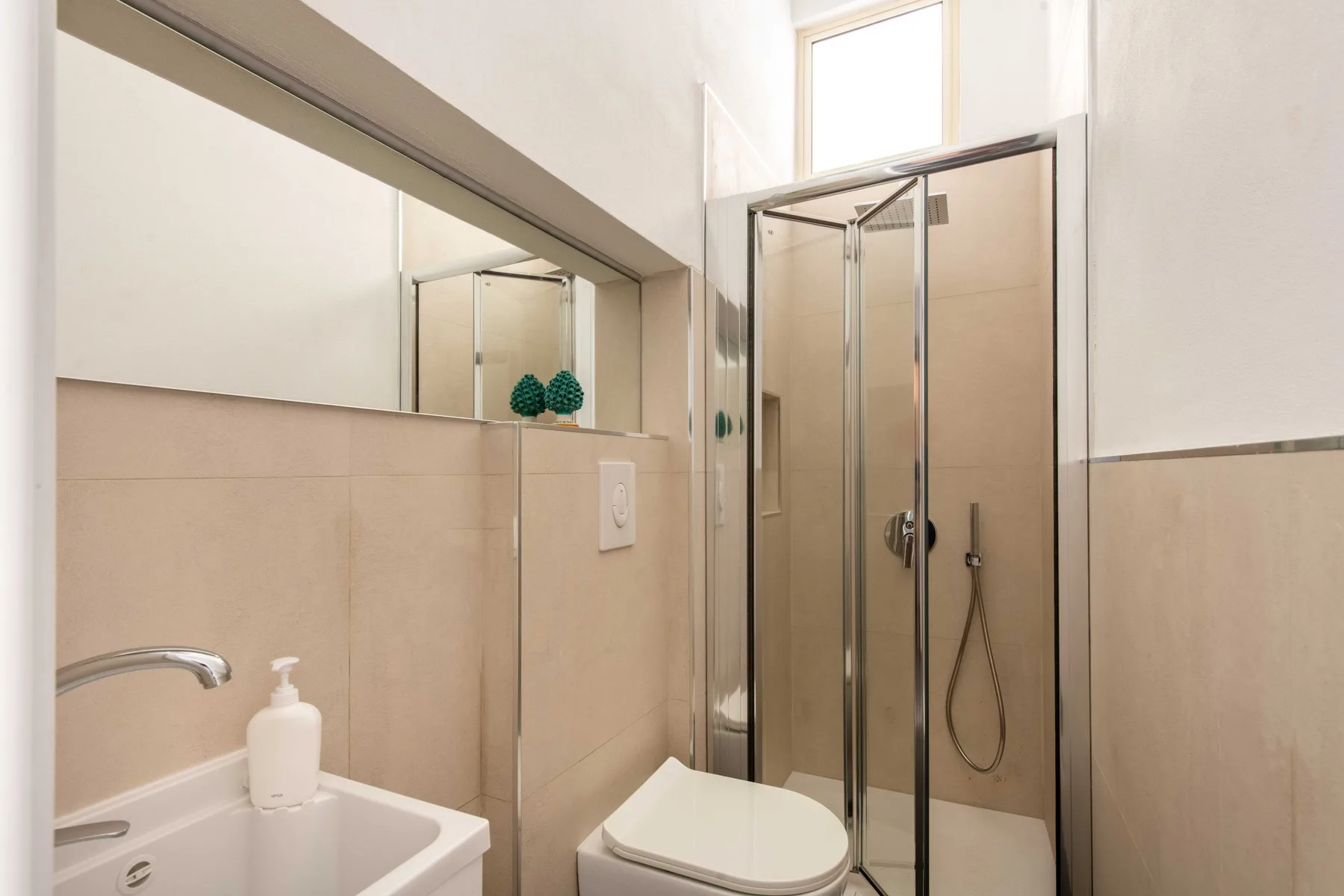 A bright bathroom with a sink and glass-enclosed shower.