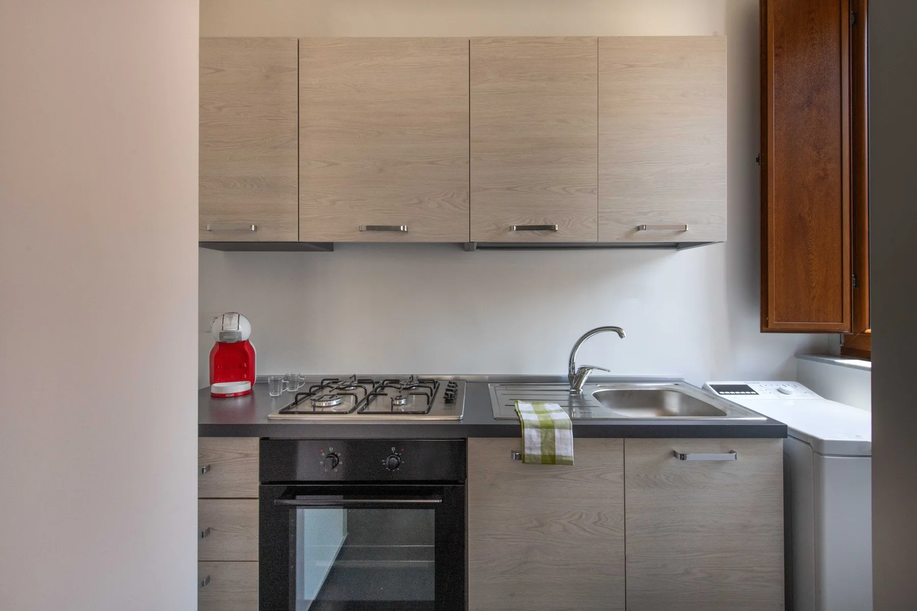A compact kitchen with light cabinets, a gas cooktop, and a sink.