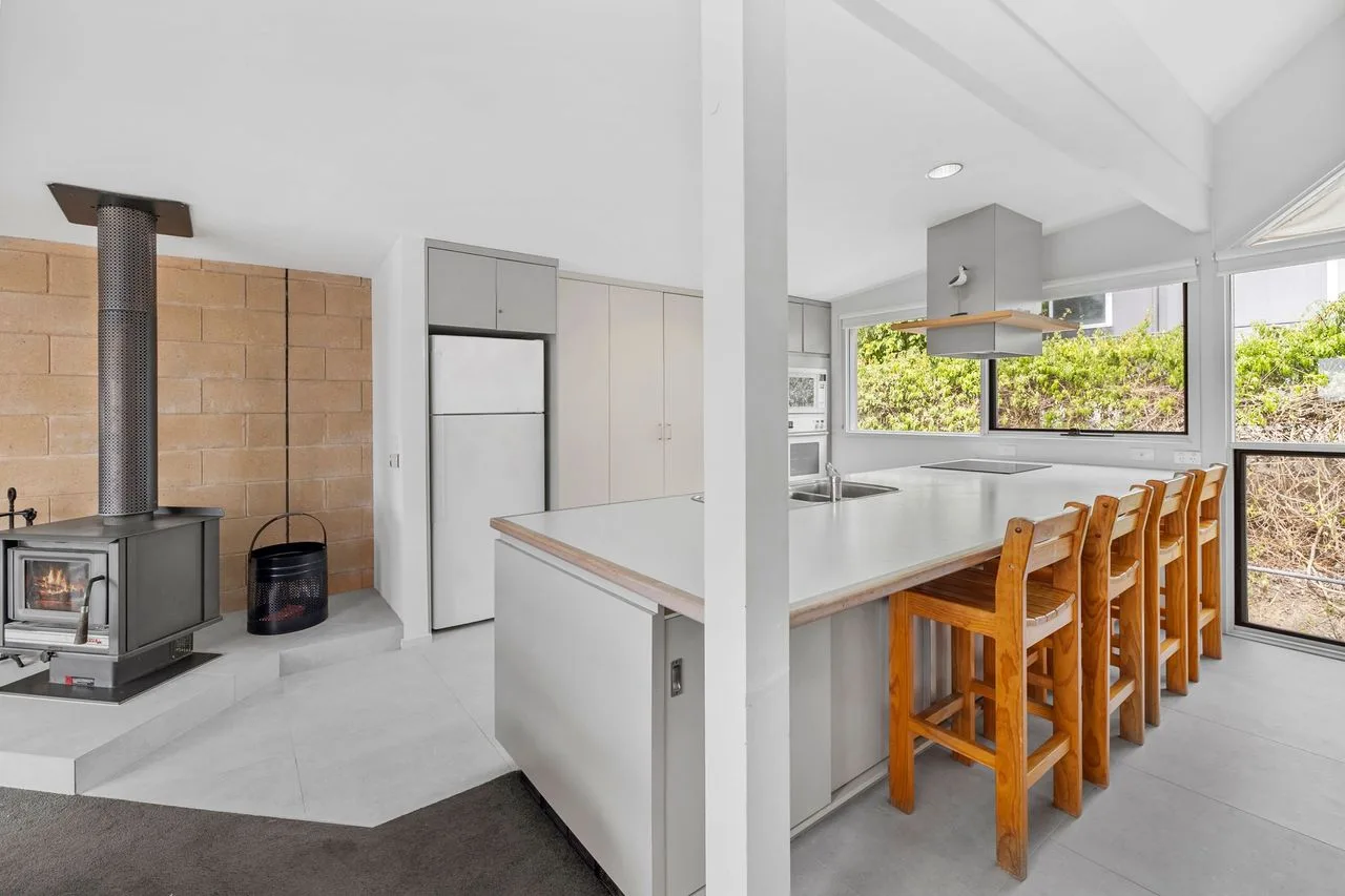 A bright kitchen with a long island and wooden bar stools.