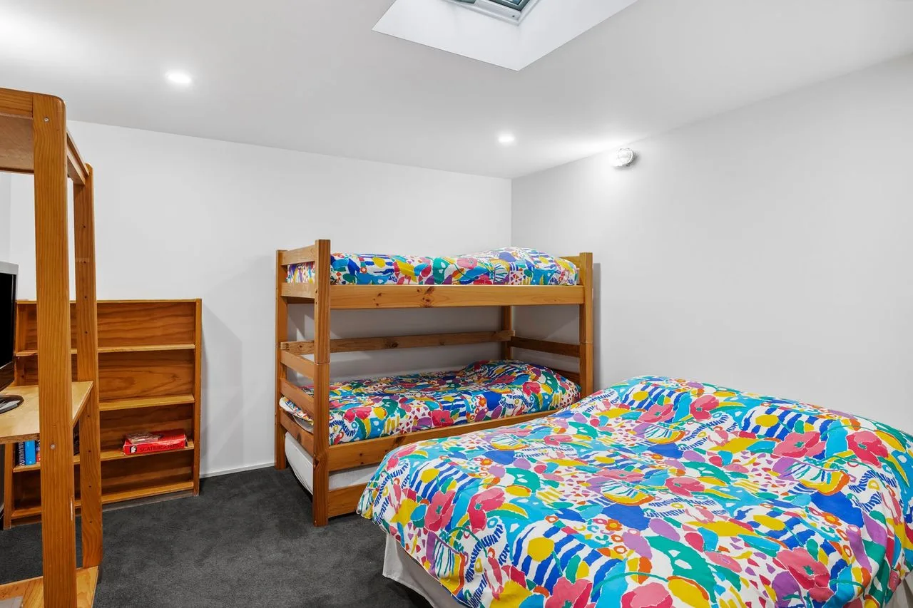 A bedroom with colorful bedding and wooden bunk beds.