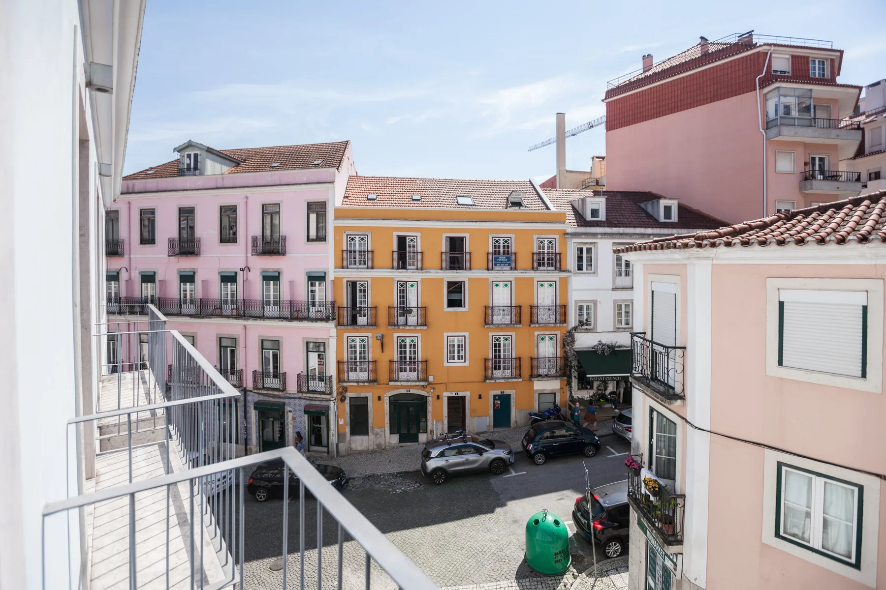 Un balcón da a una plaza empedrada rodeada de edificios coloridos.