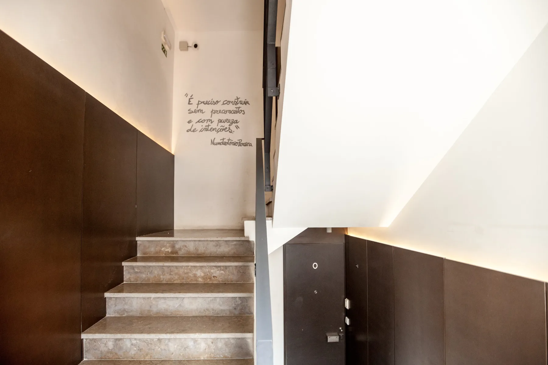 Una escalera interior con peldaños de piedra y paneles oscuros en las paredes.
