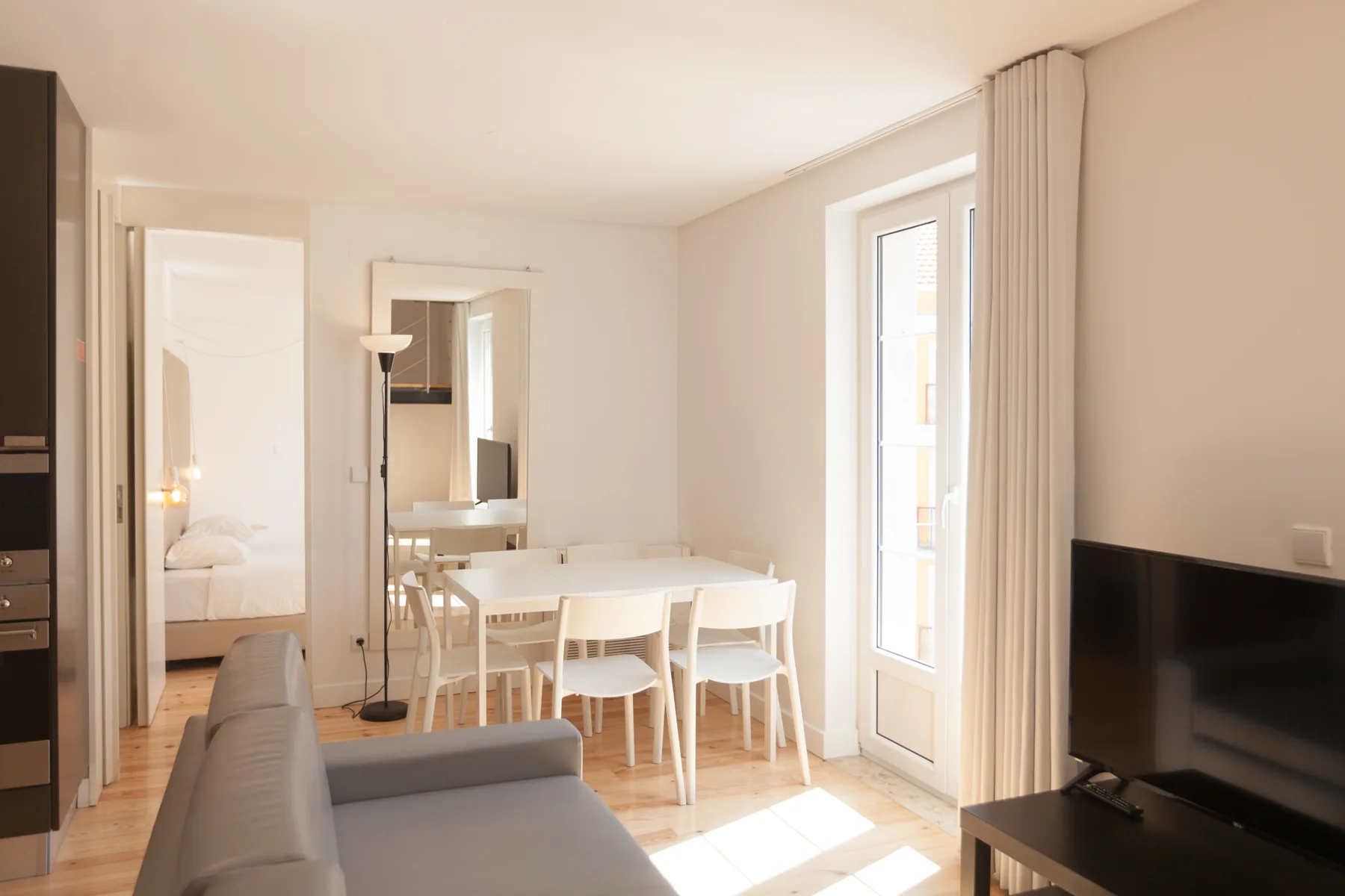 Zona de estar y comedor con una mesa junto a una ventana luminosa.