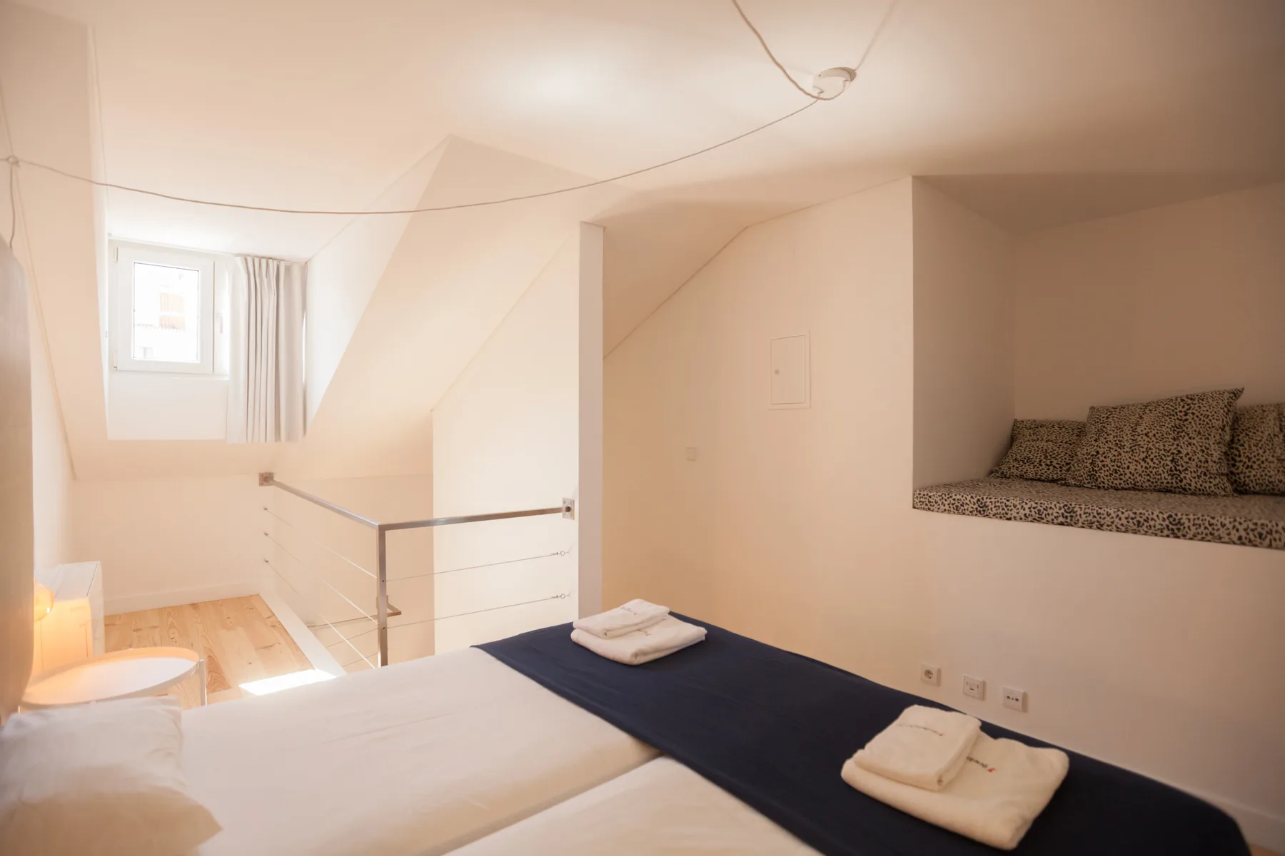 Un dormitorio con una cama, toallas dobladas y una ventana pequeña.