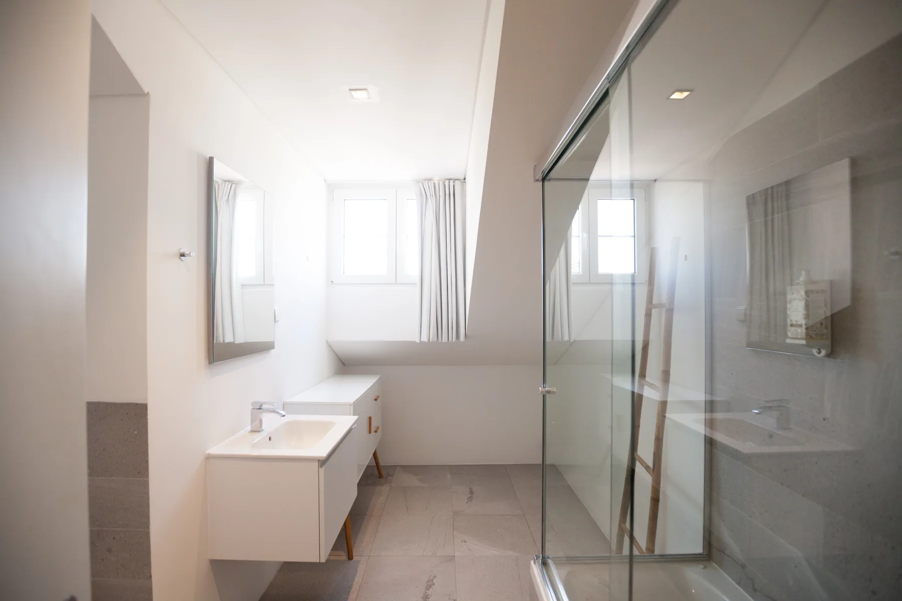 Un baño luminoso con un lavabo largo y una ducha de cristal.