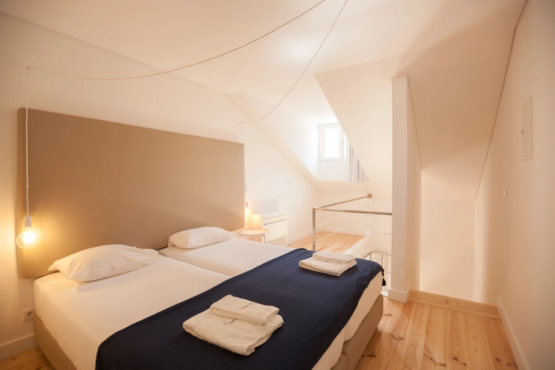 Un dormitorio luminoso con una cama bajo un techo inclinado.