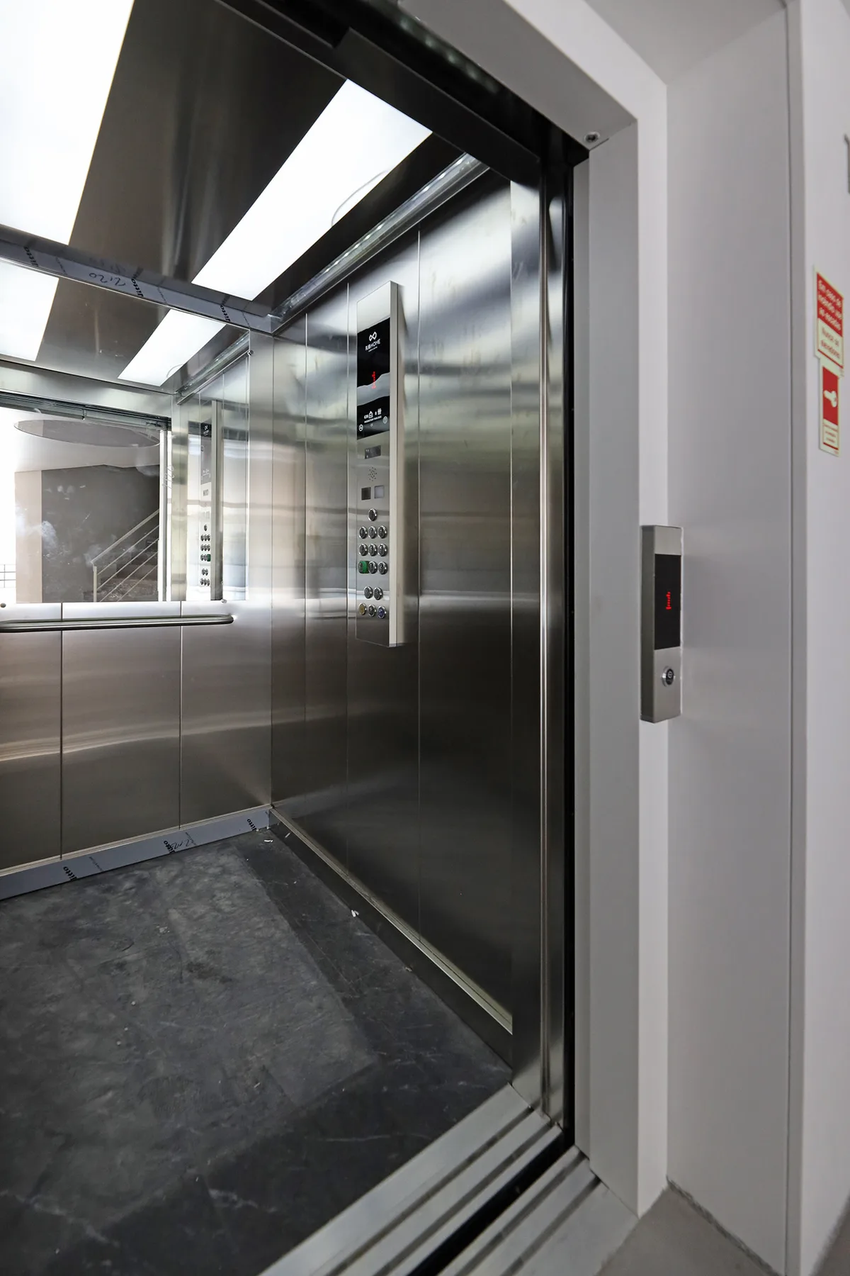 An elevator with stainless steel walls and a dark floor.