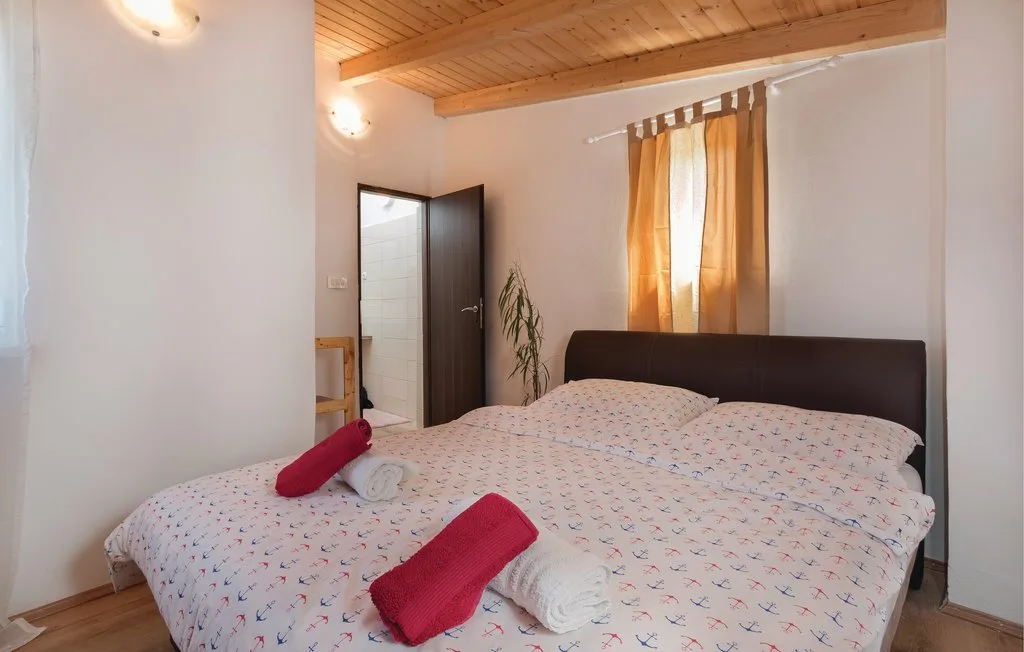 Un dormitorio con una cama grande, ropa de cama estampada y una ventana con cortinas iluminada por el sol.