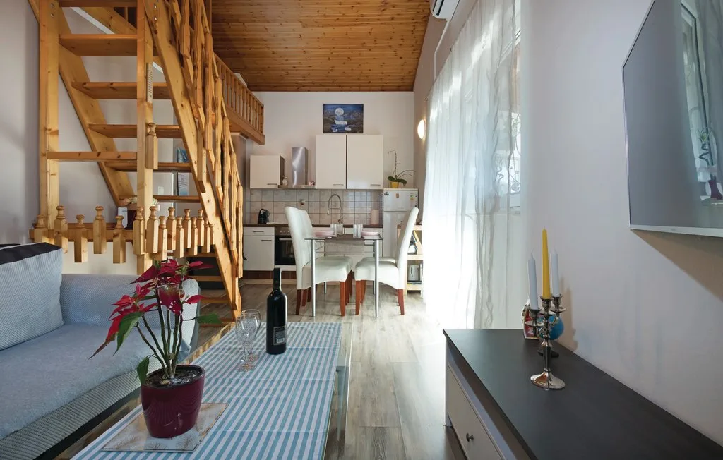 Una zona de estar y comedor con una escalera de madera, asientos y una mesa.