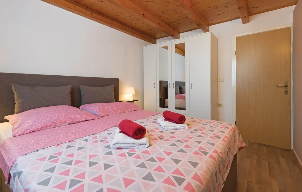 Un dormitorio con una cama doble vestida con ropa de cama rosa y estampada.