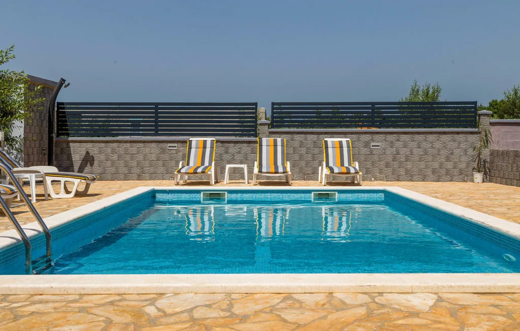 Una piscina exterior con tumbonas a rayas junto a la terraza de piedra.