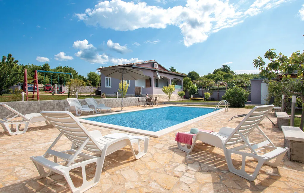 Una piscina al aire libre y una zona de asientos junto a una casa.