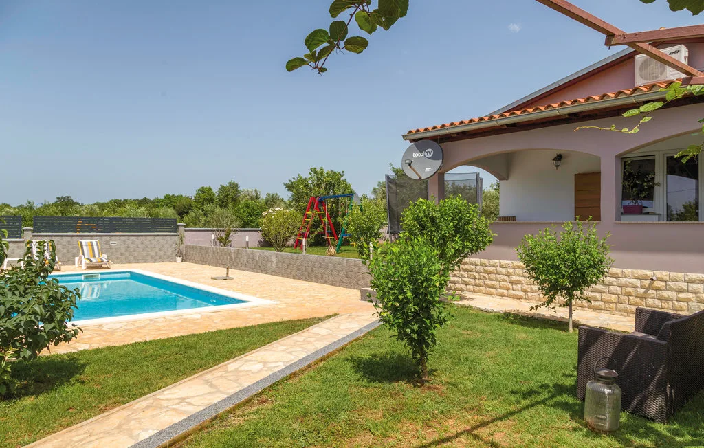 Piscina y jardín al aire libre junto a una casa con patio cubierto.