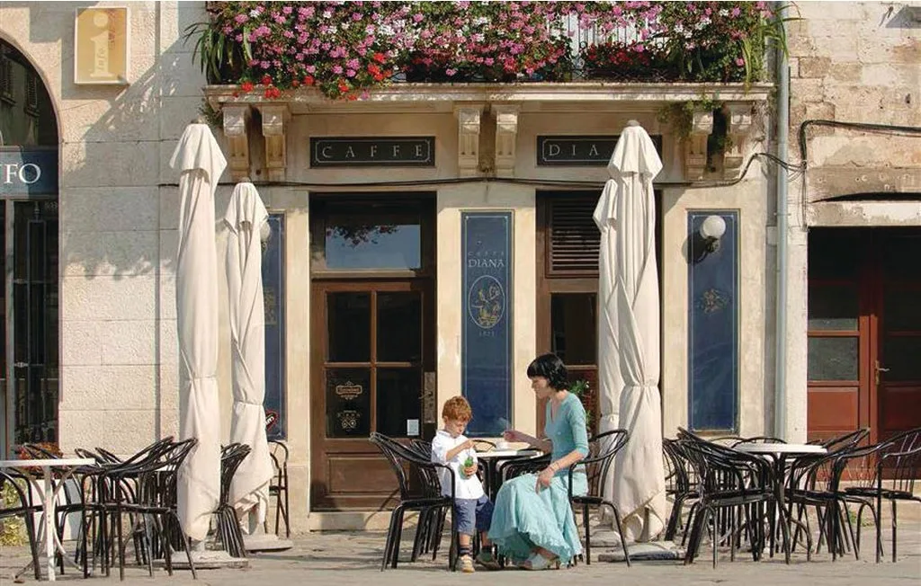 Una terraza de café con asientos al aire libre y sombrillas cerradas.