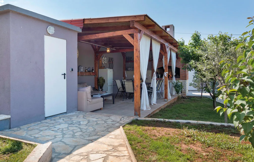Un patio exterior cubierto con asientos se abre a un pequeño jardín.
