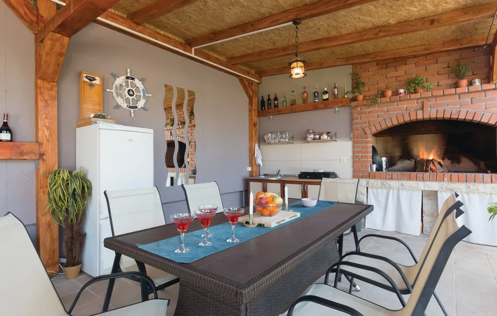 Comedor con una mesa larga y asientos junto a una chimenea de ladrillo.