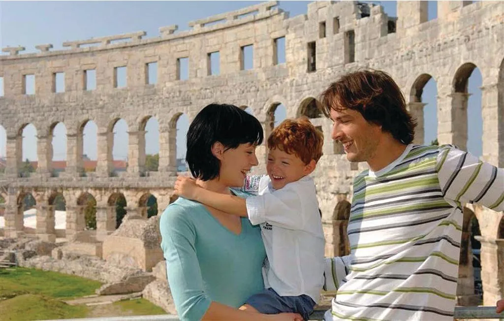 Una familia posa junta entre los arcos de piedra de un antiguo anfiteatro.