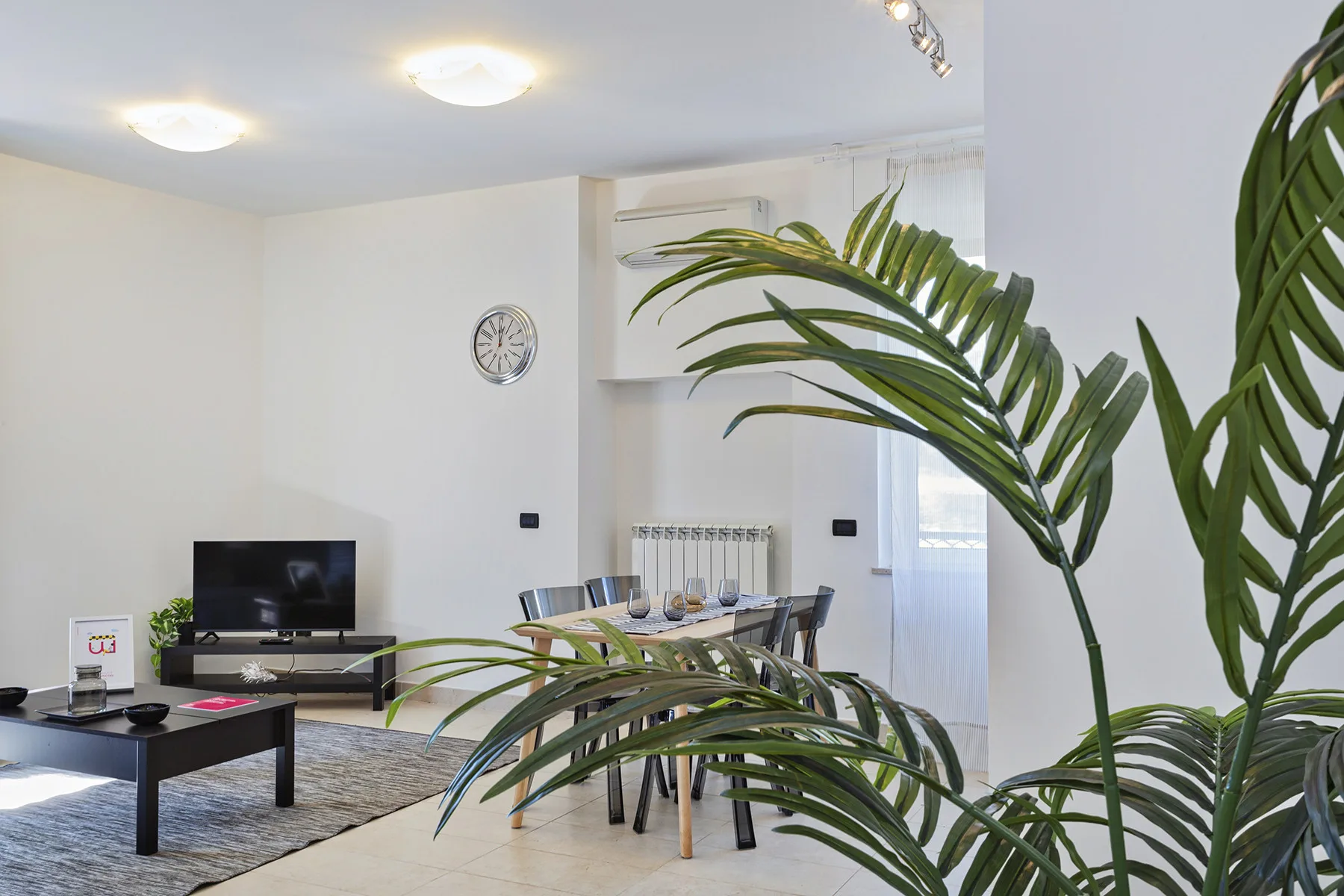 Una luminosa sala de estar y comedor con asientos, un televisor y una mesa de comedor.