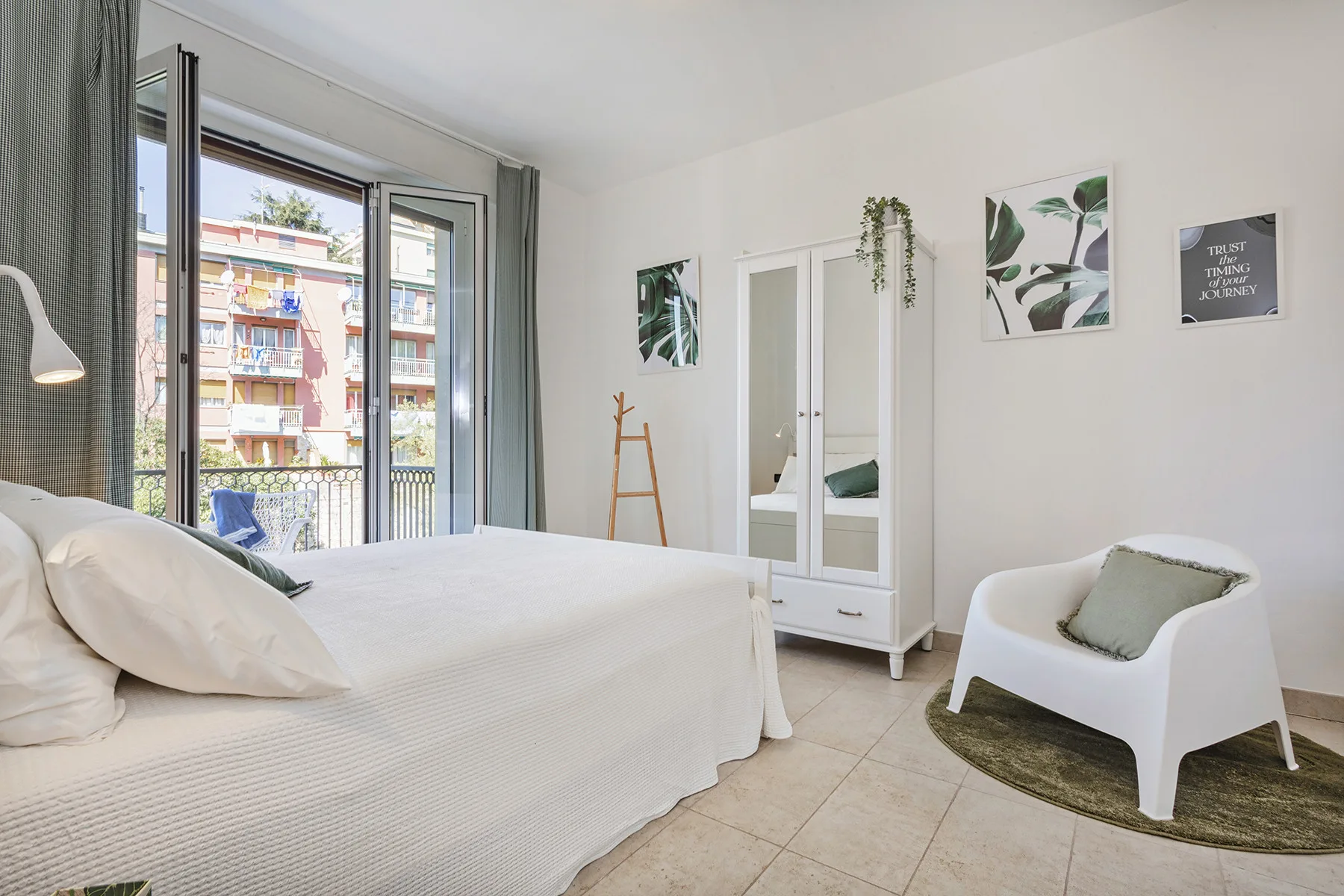 Un dormitorio luminoso con una cama, un armario y una ventana grande.