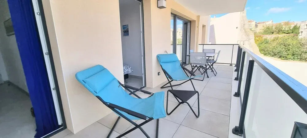 A balcony with blue lounge chairs and a small outdoor dining set.