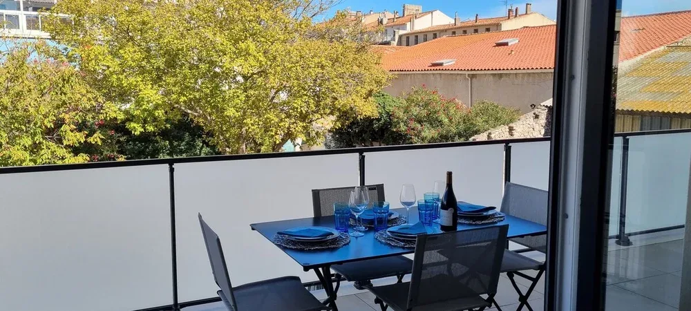 A balcony dining area with a table set with blue dishes and chairs.
