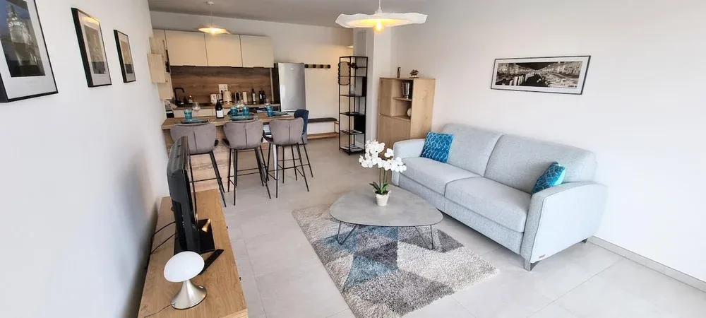 An open-plan living room and kitchen with a light-colored sofa and dining counter.