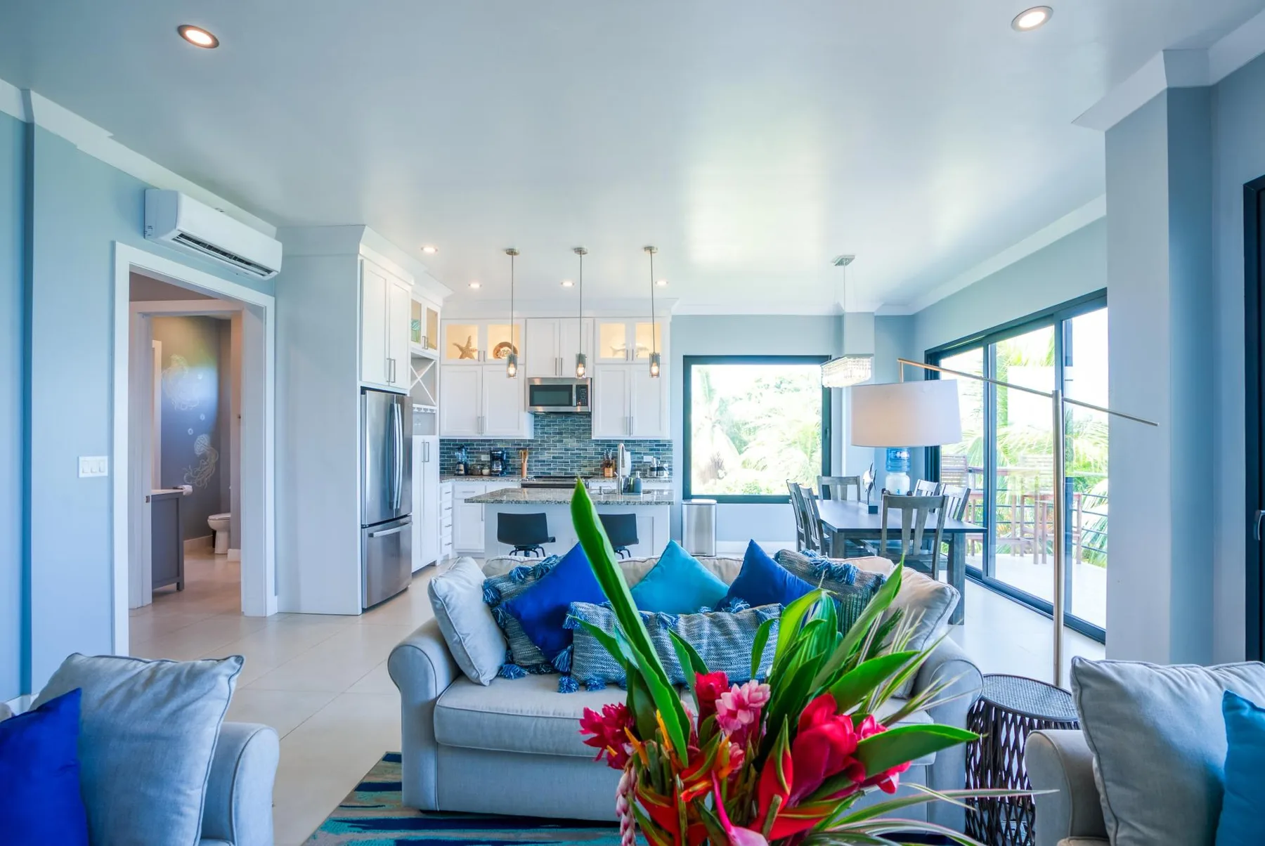 An open-plan living room and kitchen with blue seating and a dining area.