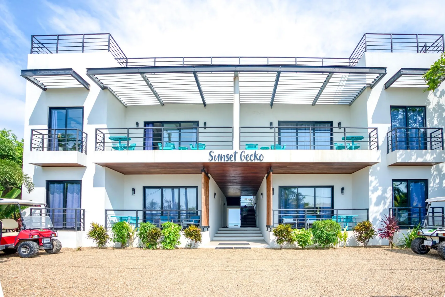 A modern white building with balconies and a broad metal canopy.