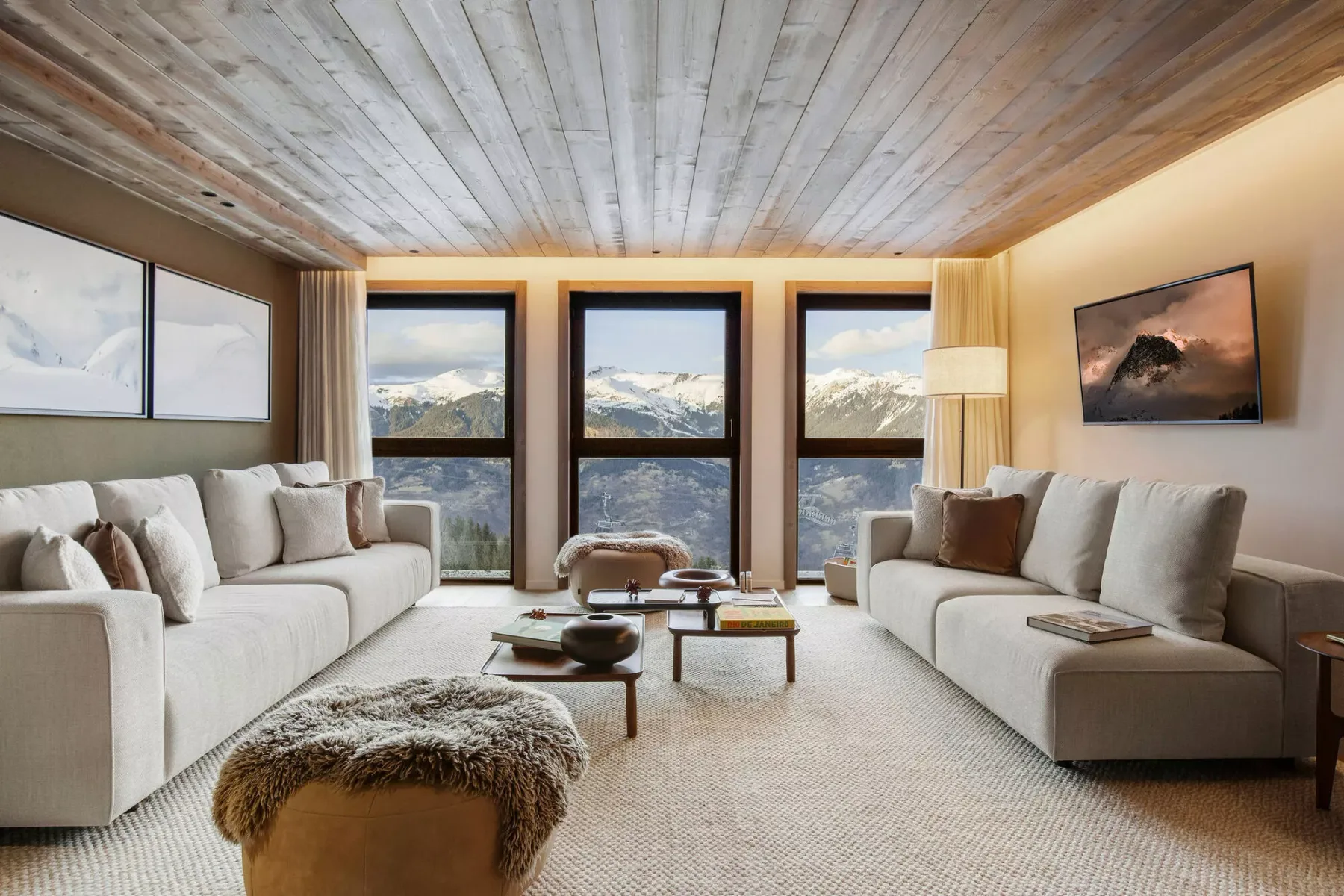 A bright living room with seating arranged around a low coffee table and mountain views through the windows.