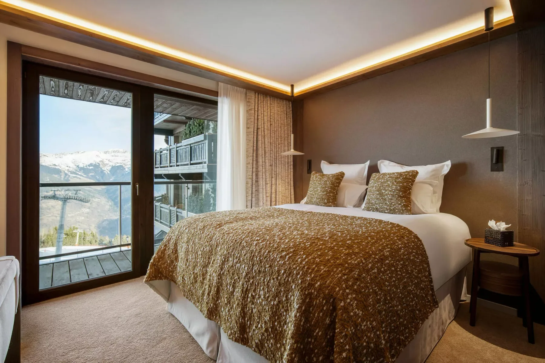 A bedroom with a neatly made bed and glass doors opening onto a balcony.