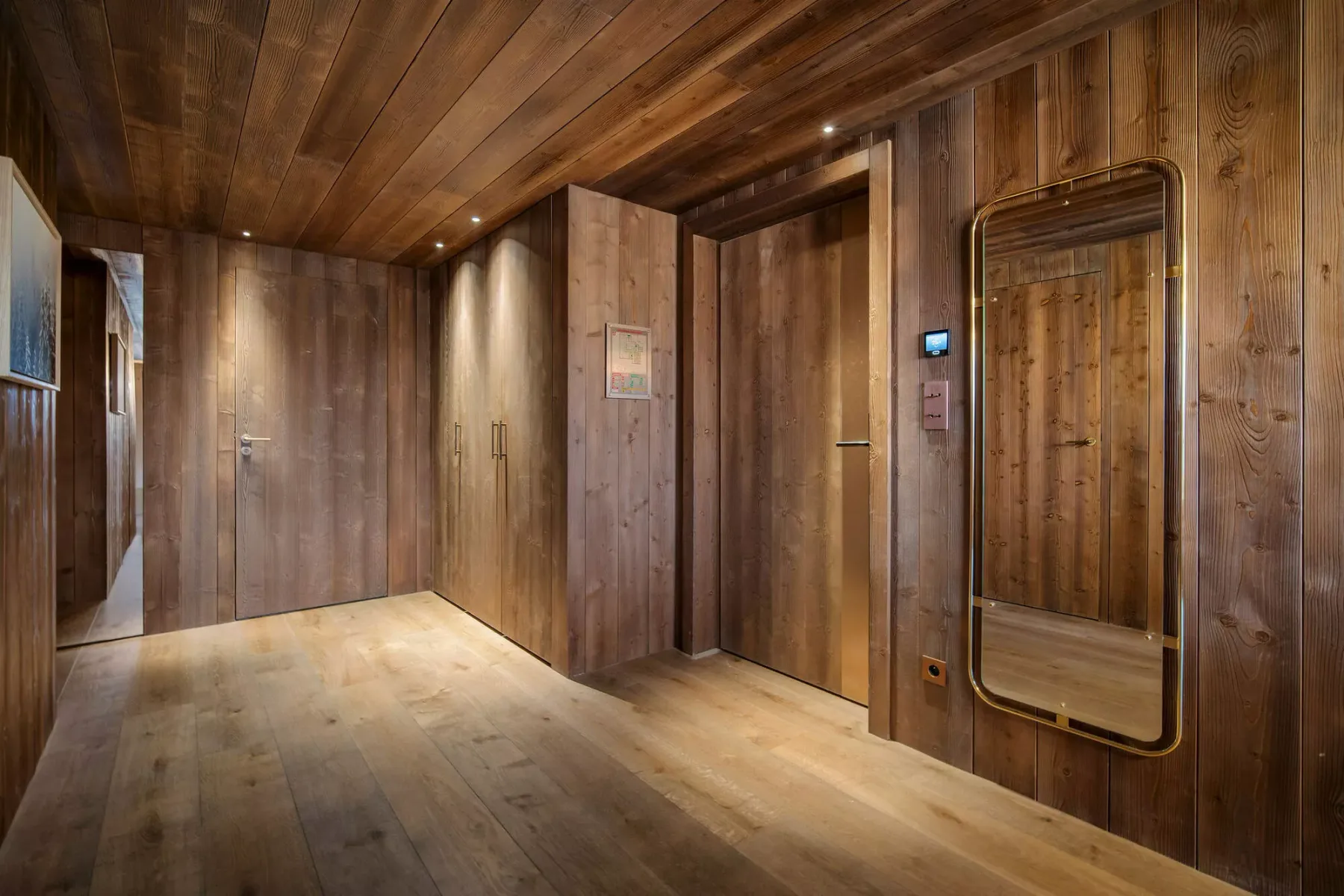 A wood-paneled hallway with several doors and a full-length mirror.