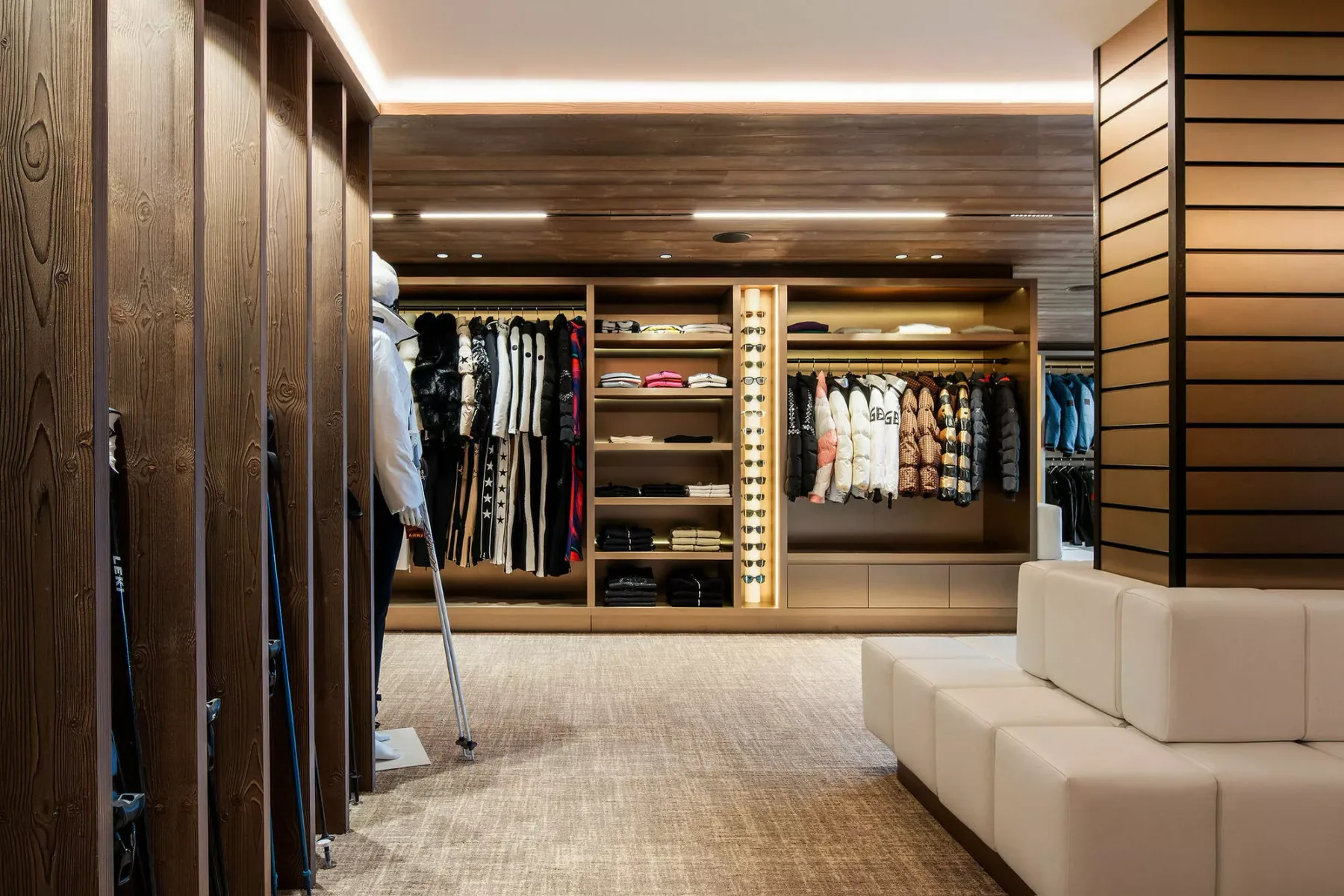 A walk-in wardrobe with clothing racks and a long upholstered bench.
