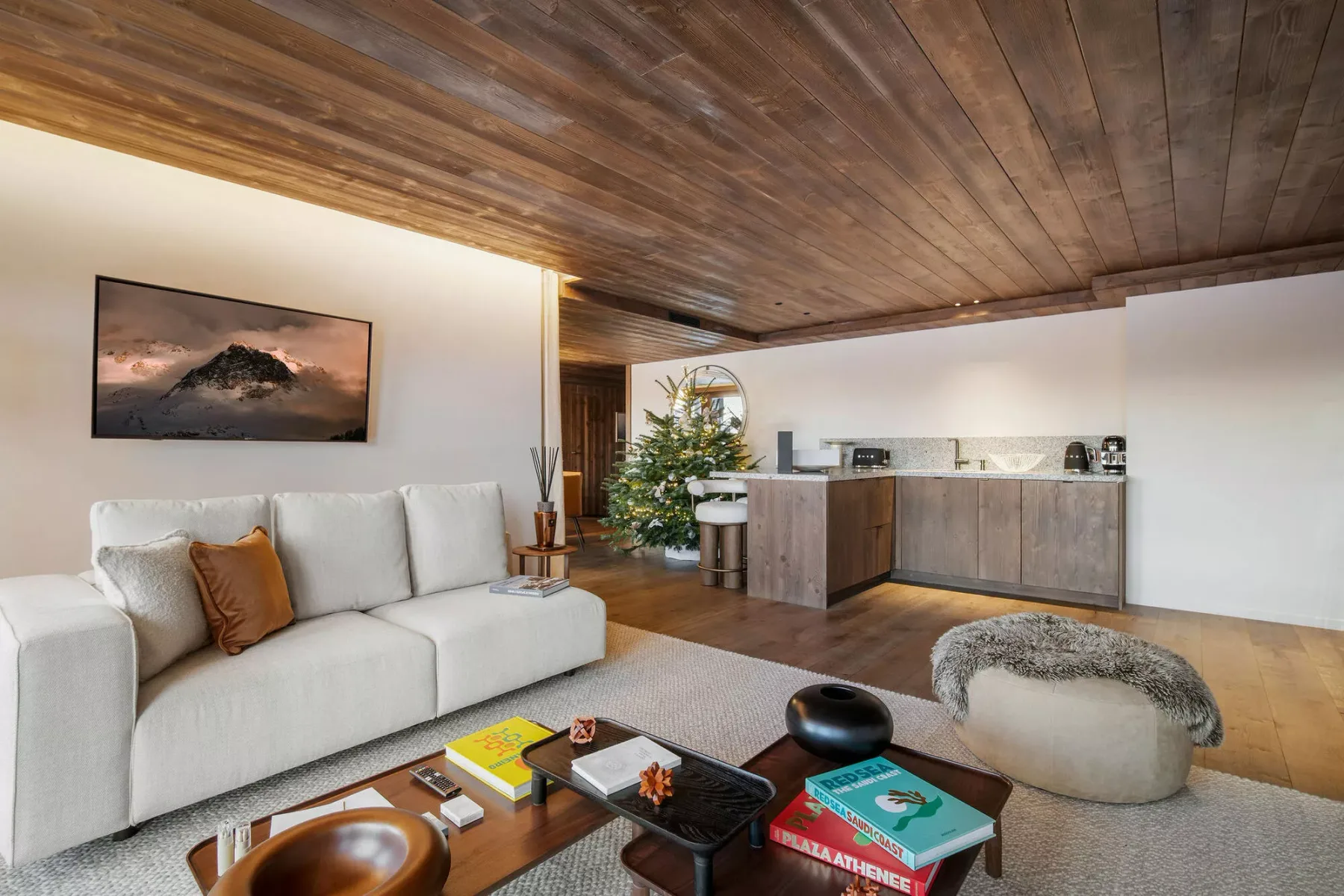 A living room with light seating, a low table, and an open kitchen.