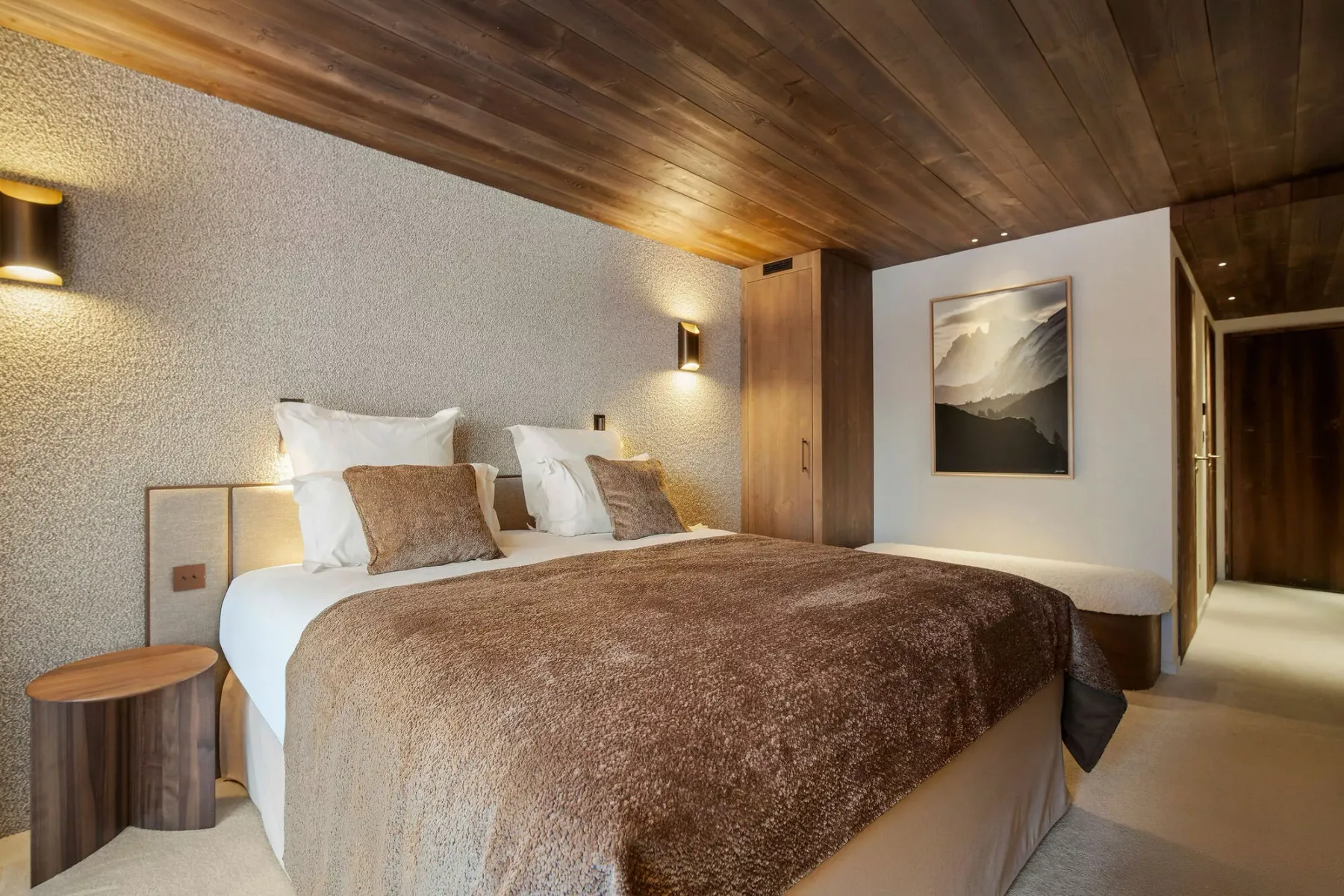 A bedroom with a large bed, bedside lighting, and framed wall art.