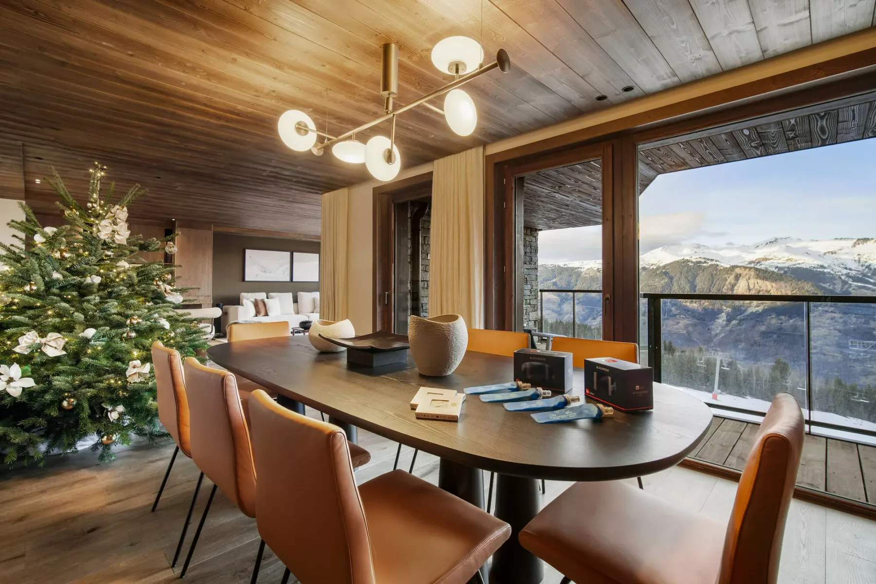 A dining area with a long table and large windows overlooking a mountain landscape.