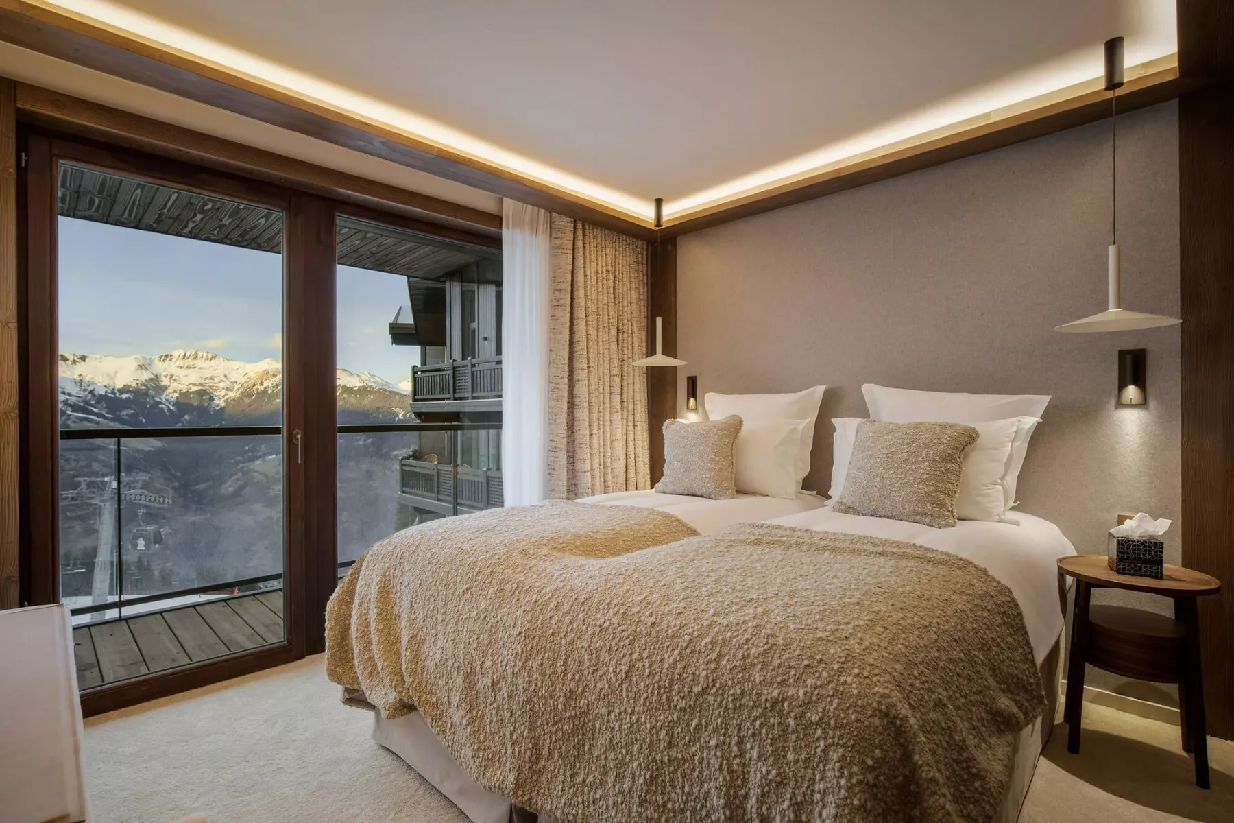 A bedroom with a large bed beside glass doors overlooking a mountain view.