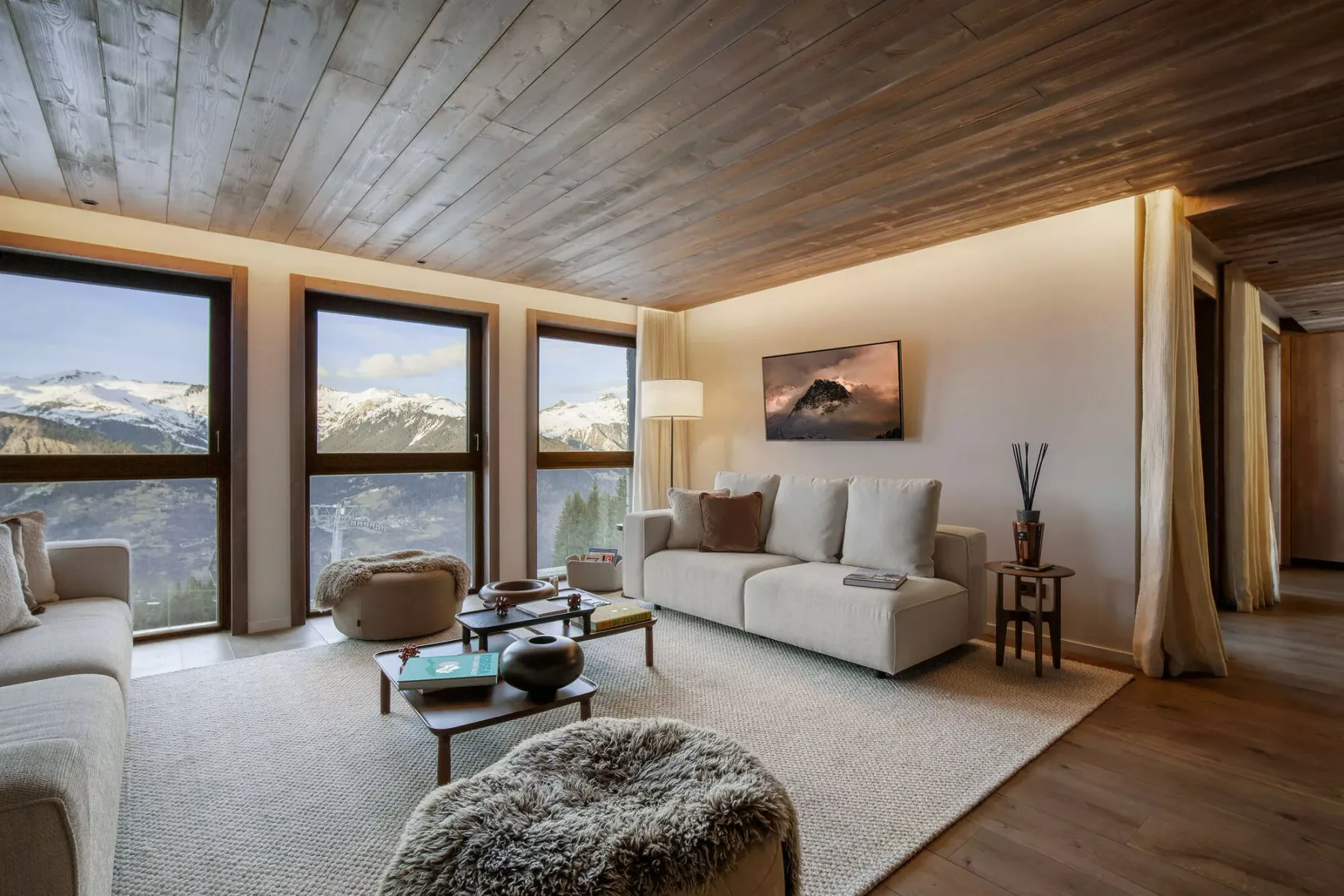 Living room with seating beside large windows overlooking a mountain landscape.