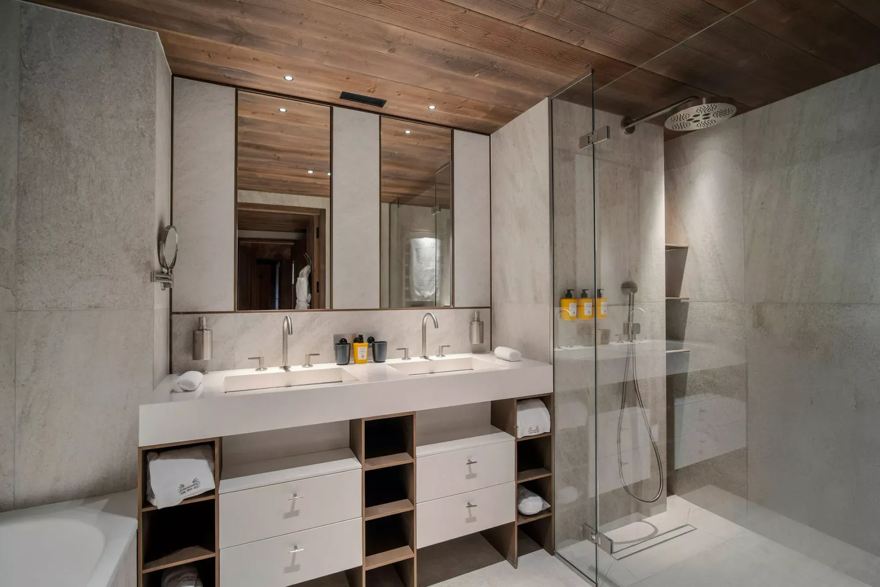 A bathroom with a long sink counter and a glass-enclosed shower.