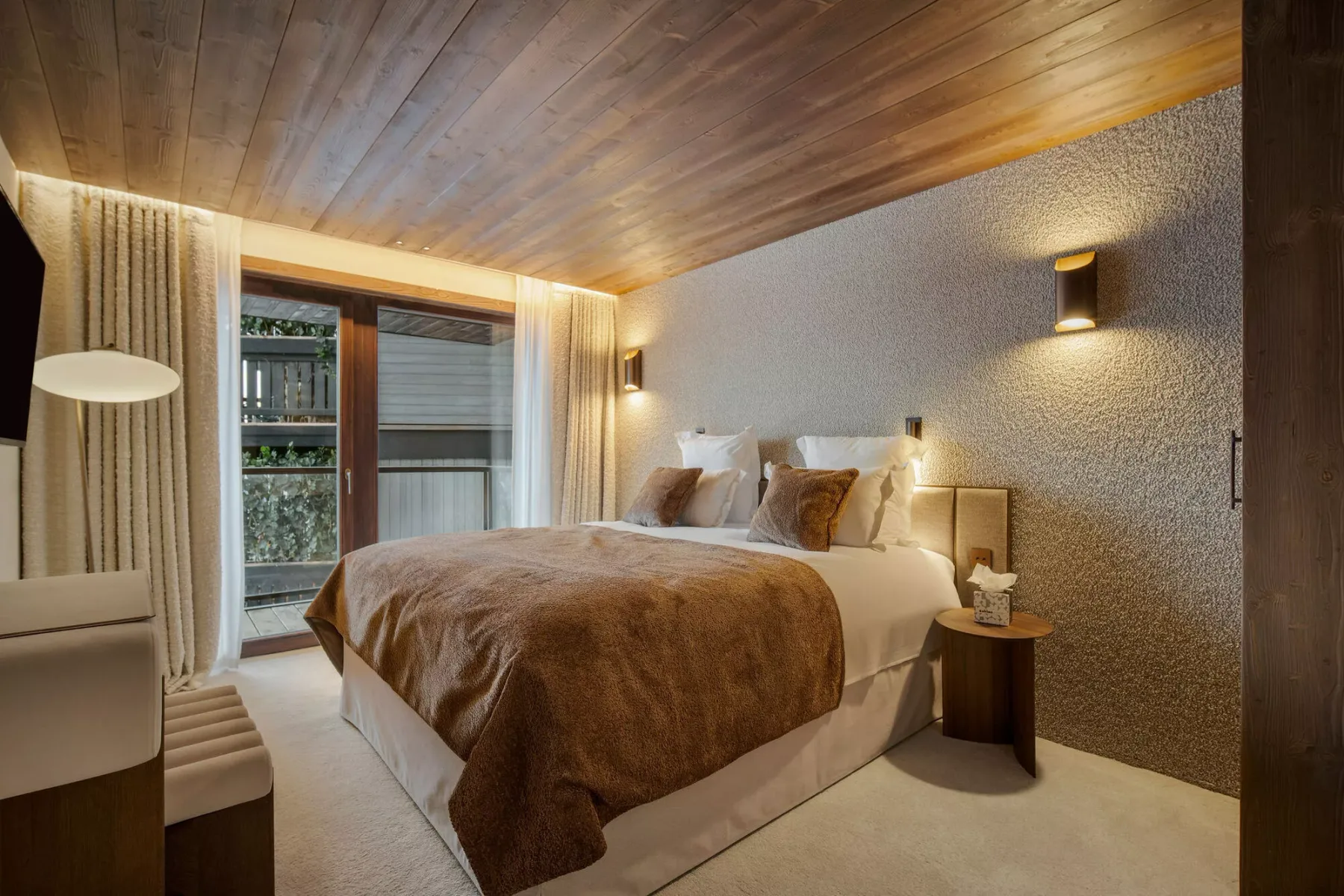 A bedroom with a bed beside a window and curtains.