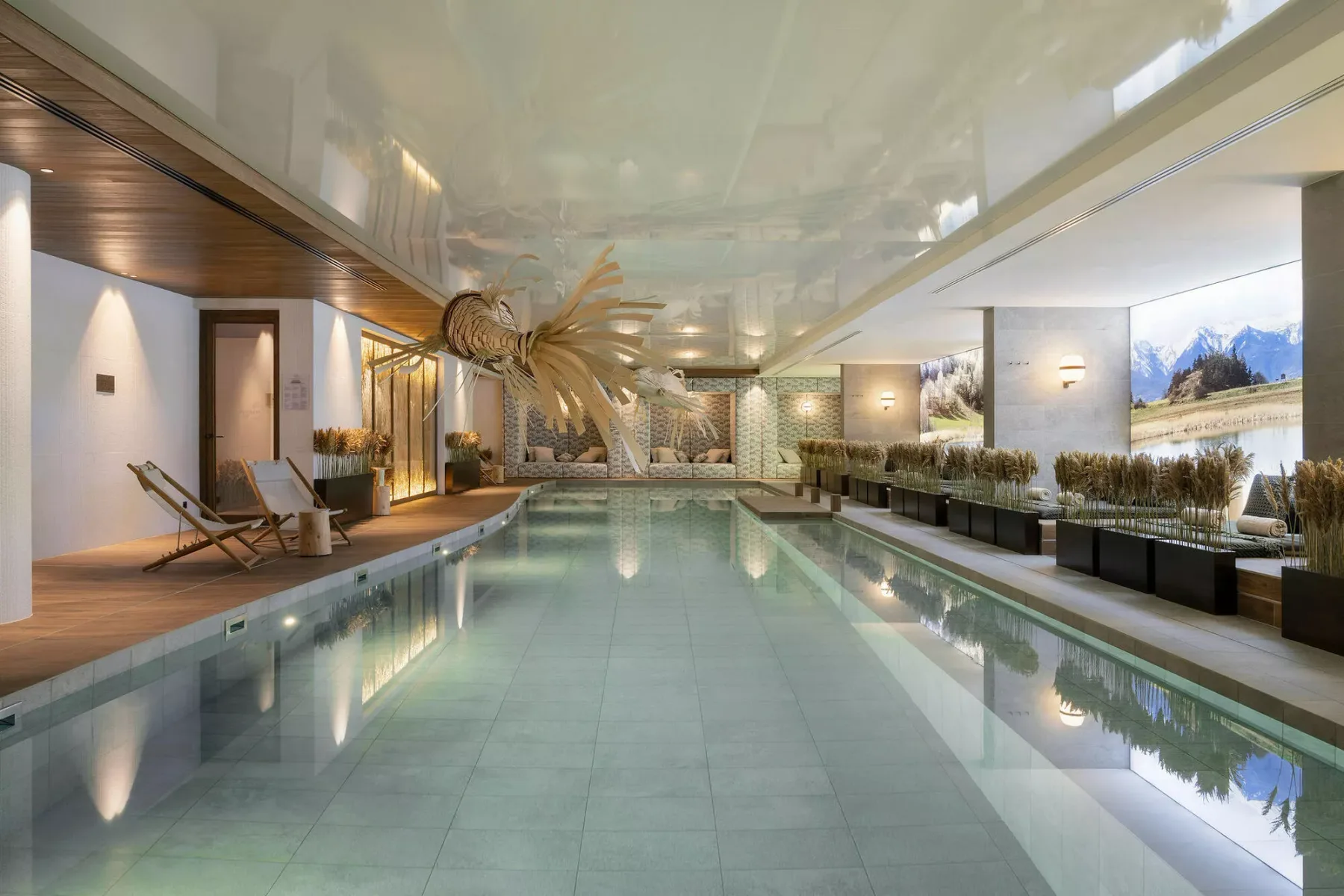 An indoor swimming pool with lounge seating along the sides.