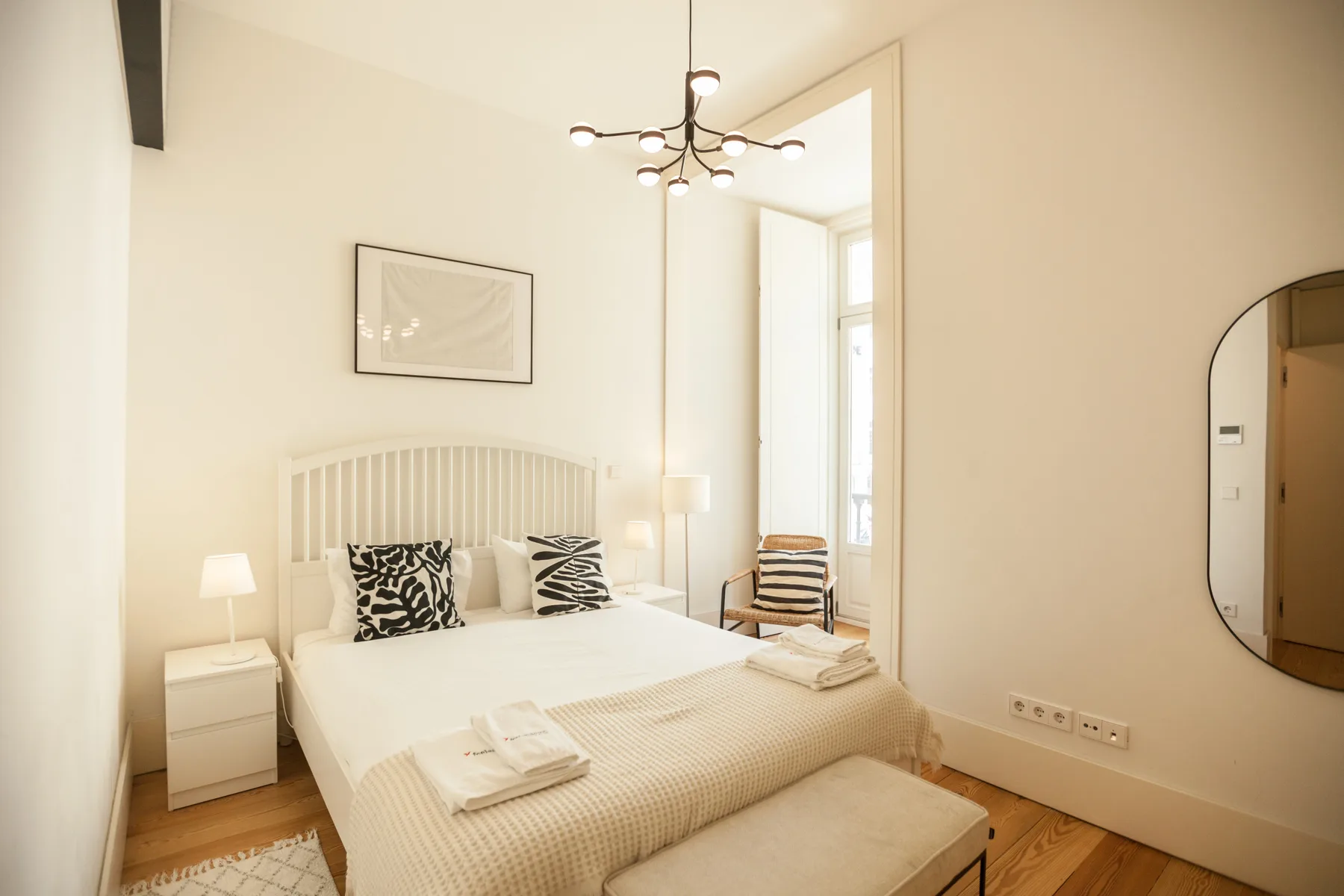 Un dormitorio luminoso con una cama bien hecha y una ventana grande.
