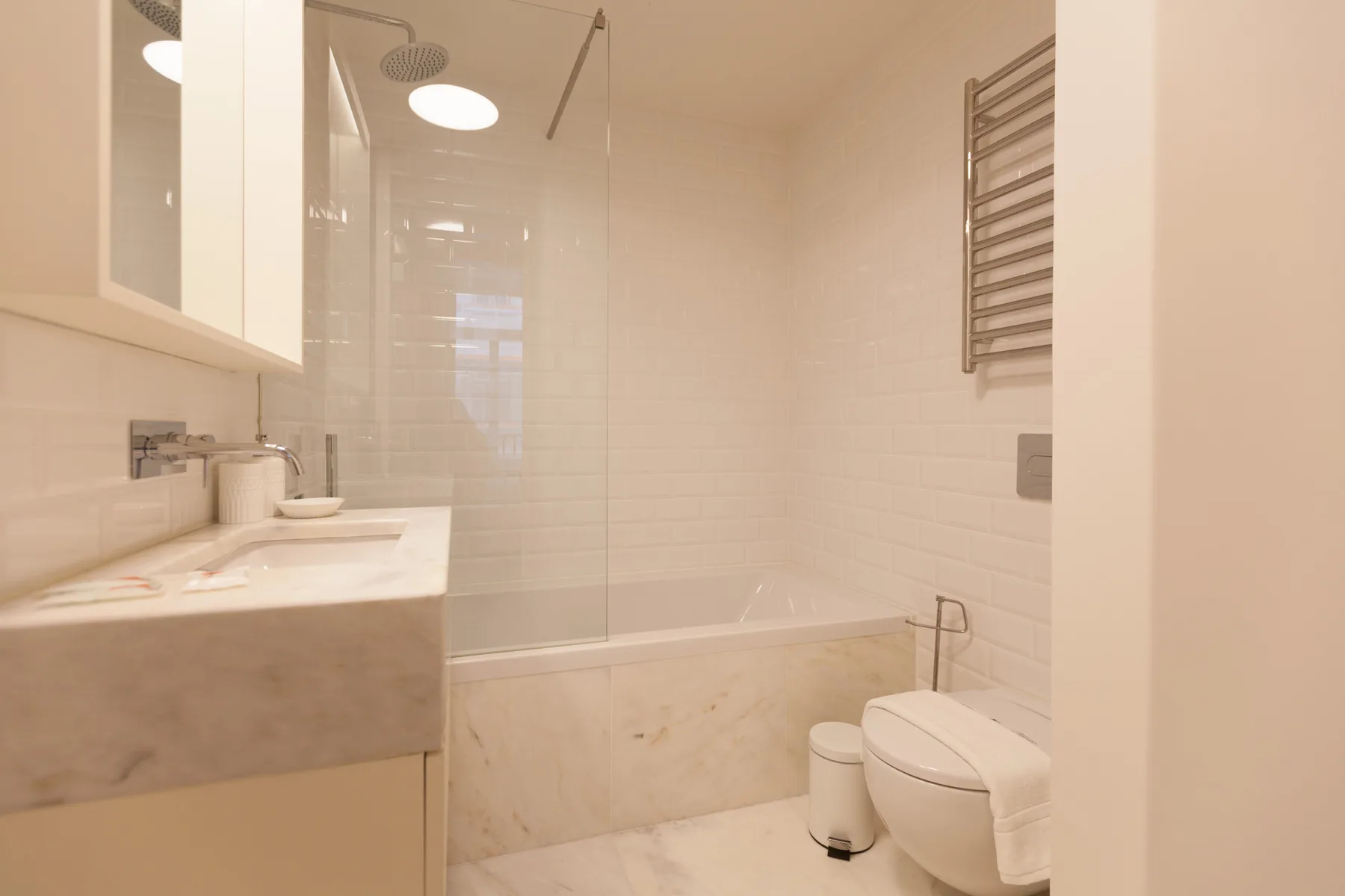 Un baño luminoso con bañera, lavabo e inodoro.