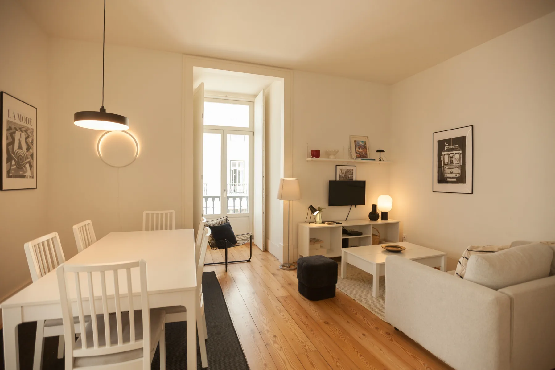 Una luminosa sala de estar y comedor con televisor, asientos y una mesa.