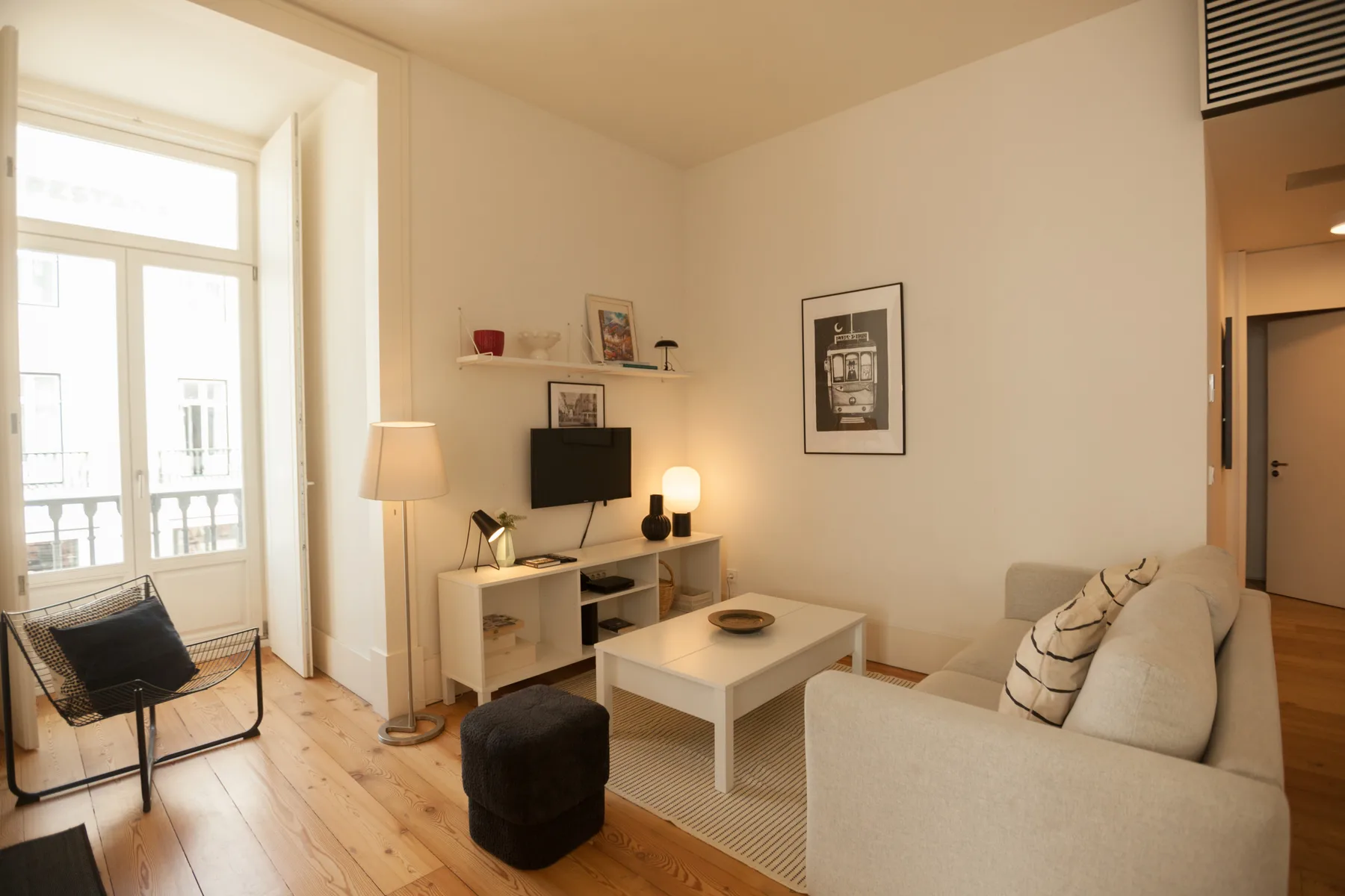 Una sala luminosa con asientos, una mesa de centro y un televisor.