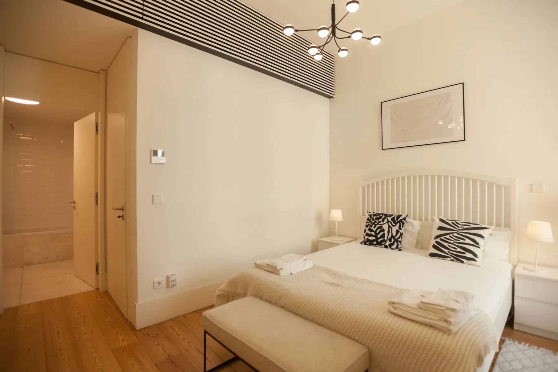 Dormitorio con una cama, mesitas de noche y un banco a los pies.