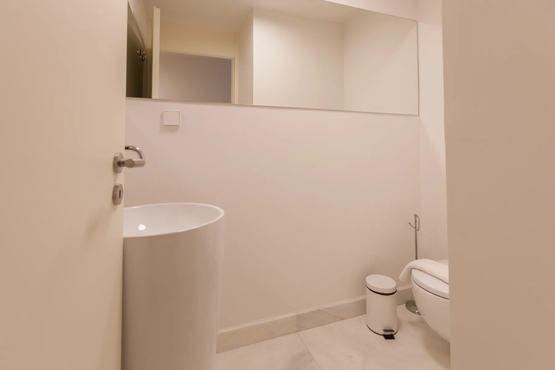 Un baño con lavabo, inodoro y espejo en la pared.