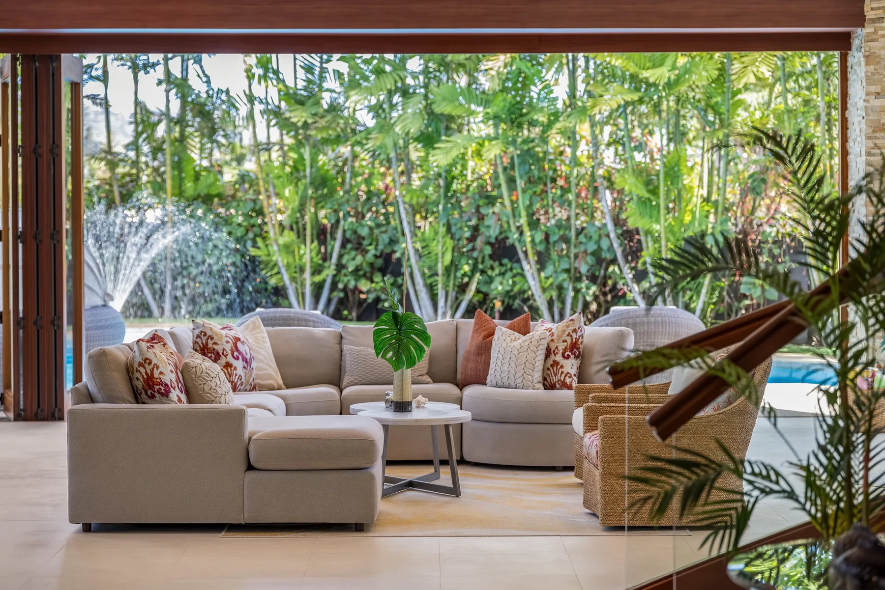 Una sala de estar con asientos acolchados y una mesa baja junto a un jardín.