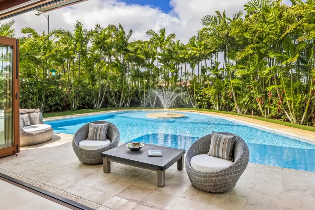 Una piscina con una fuente está junto a un patio con asientos.