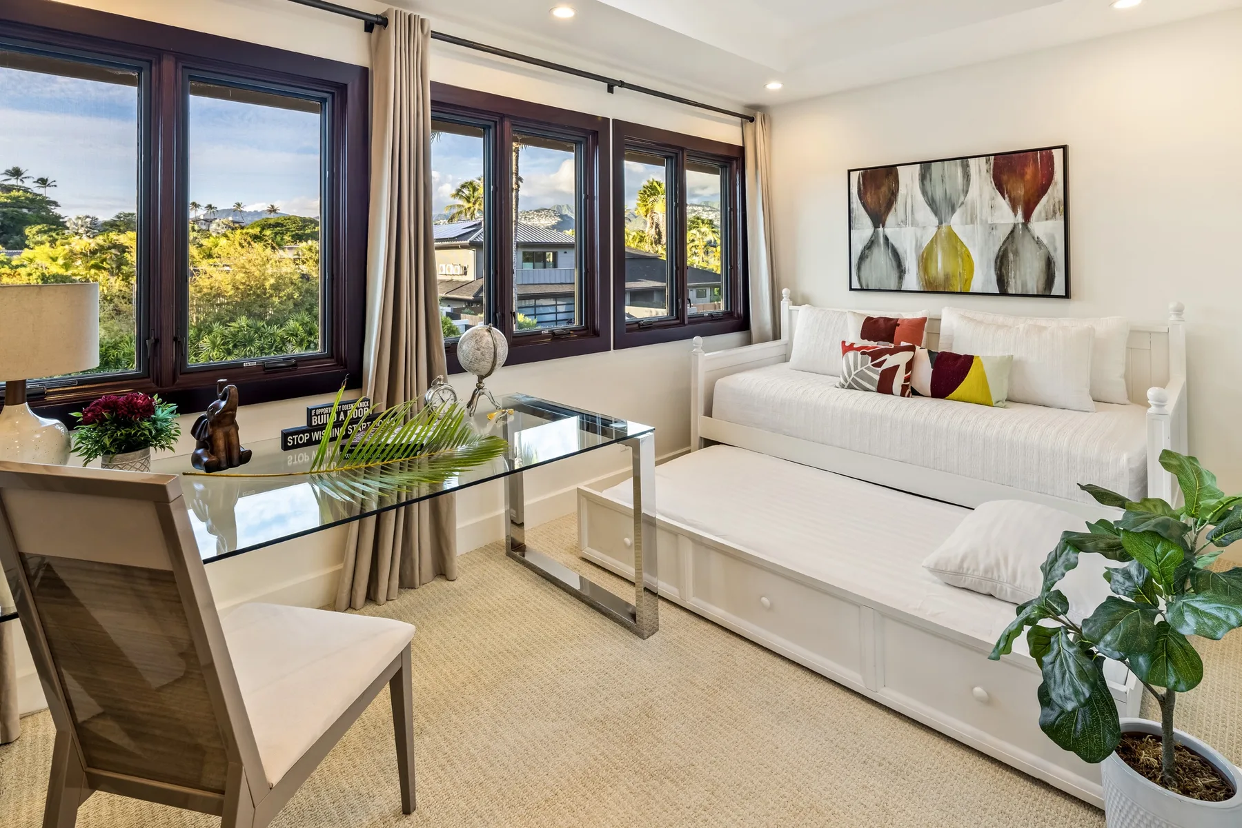 Una sala luminosa con sofá blanco, mesa de centro de vidrio y ventanas grandes.