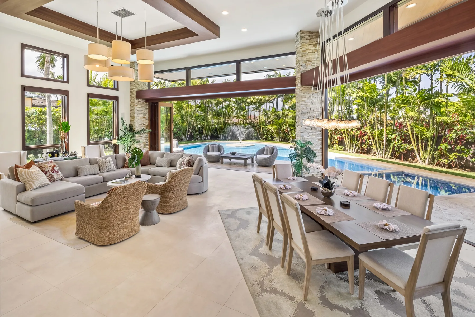 Una sala y comedor de planta abierta dan a una piscina y abundante vegetación.